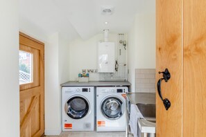 A compact laundry area with two front-loading washing machines, a built-in dryer, and a small sink. - 2 Bed in Thrussington (oc-42472) (Thrussington)