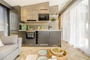 A modern kitchen with built-in appliances, a dining area with a sofa, and a large window with sheer curtains.