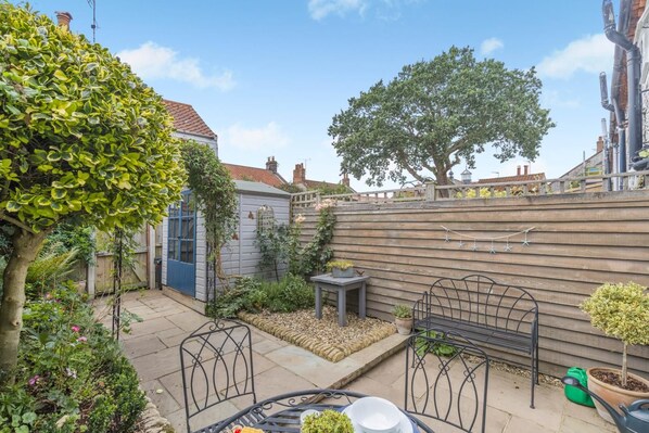 A garden with a wooden fence, a blue door, a metal bench, and potted plants. - 1 Bed in Holt (oc-a46046) (Holt)