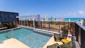 Una piscina sul tetto con vista sulla città, lettini e ringhiera in vetro.