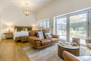 Quarto moderno com uma cama grande, um sofá de couro marrom e uma mesa lateral redonda.