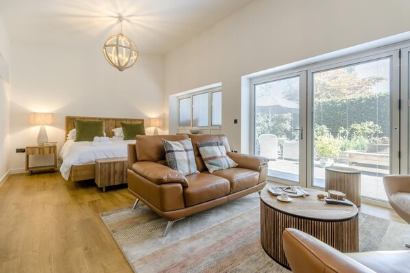 A modern bedroom with a large bed, a brown leather sofa, and a round side table.