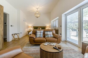 Ein geräumiges Wohnzimmer mit Ledersofa, Couchtisch und großem Fenster mit Blick ins Freie.