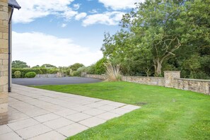 A residential driveway with a stone wall, a lawn, and a large tree. - 5 Bed in Newton-by-the-Sea (oc-s46063) (Newton-by-the-Sea)
