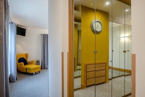 A room with a yellow wall, a clock, a bed, a chair, and a television on the wall. - 5 Bed in Newton-by-the-Sea (oc-s46063) (Newton-by-the-Sea)
