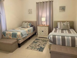 Ein Schlafzimmer mit zwei Betten, einem Nachttisch, einem Schrank, einem Teppich und einem Wandbild.