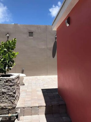 Ein gepflasterter Patio-Bereich mit einem Blumentopf, einer Steinmauer und einer roten Mauer.