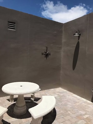 A patio area with a round table and benches, a compass, and a wall-mounted light fixture. - Comfort 2BR and 2BA w/ Private Outdoor Space (Hollywood)