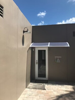 A building with a door, a small window, and a wall-mounted light fixture. - Comfort 2BR and 2BA w/ Private Outdoor Space (Hollywood)
