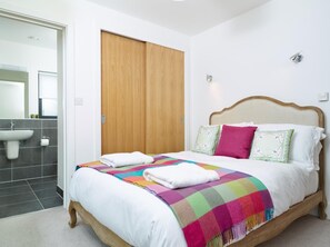 Ein Schlafzimmer mit einem Bett, einem Holzschrank, einem Badezimmer mit Waschbecken und einem Spiegel.