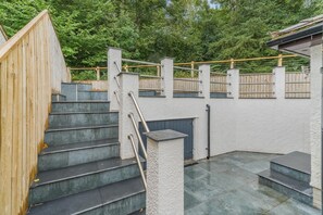 A set of outdoor stairs leading to a covered area with a wooden fence and a view of trees. - 5 Bed in Keswick (oc-m46014) (Keswick)
