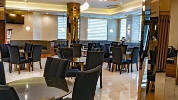 A modern dining area with round tables and chairs, a polished floor, and a wooden ceiling with recessed lighting.