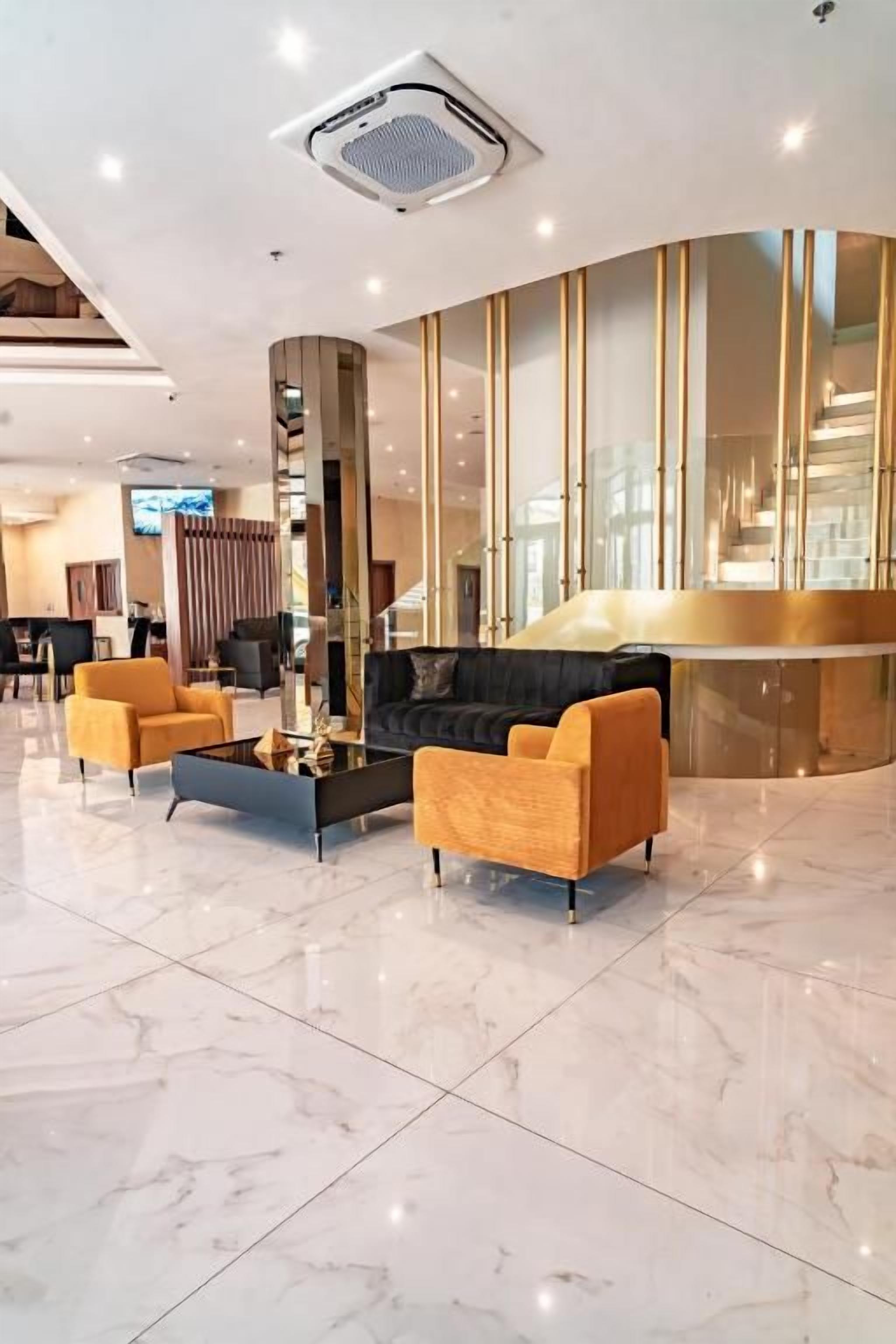 Un hall d’entrée moderne avec un sol en marbre, un comptoir d’accueil et un espace détente avec des canapés.