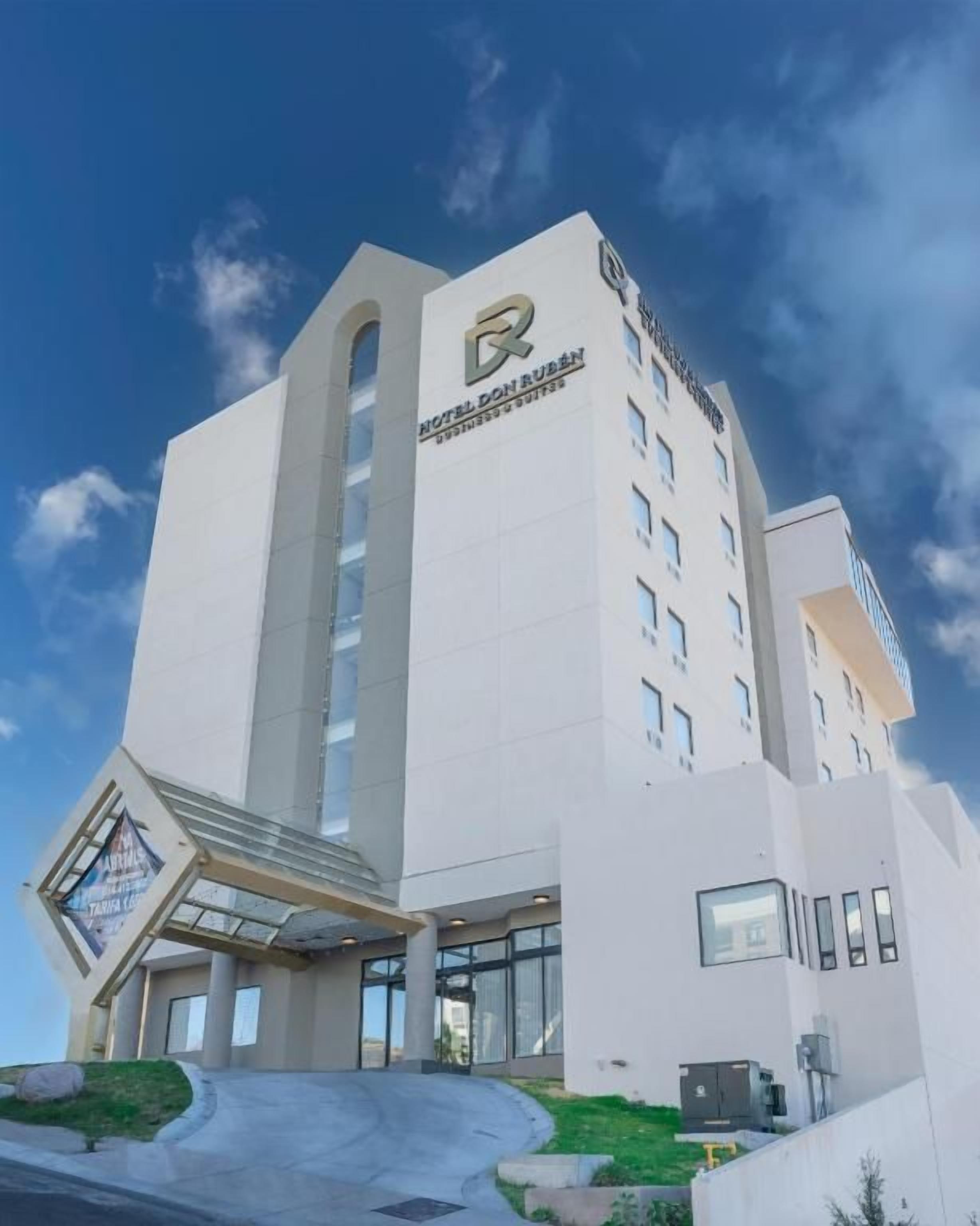 Ein modernes Hotelgebäude mit auffälligem Logo, überdachter Eingangspartei und zahlreichen Fenstern.