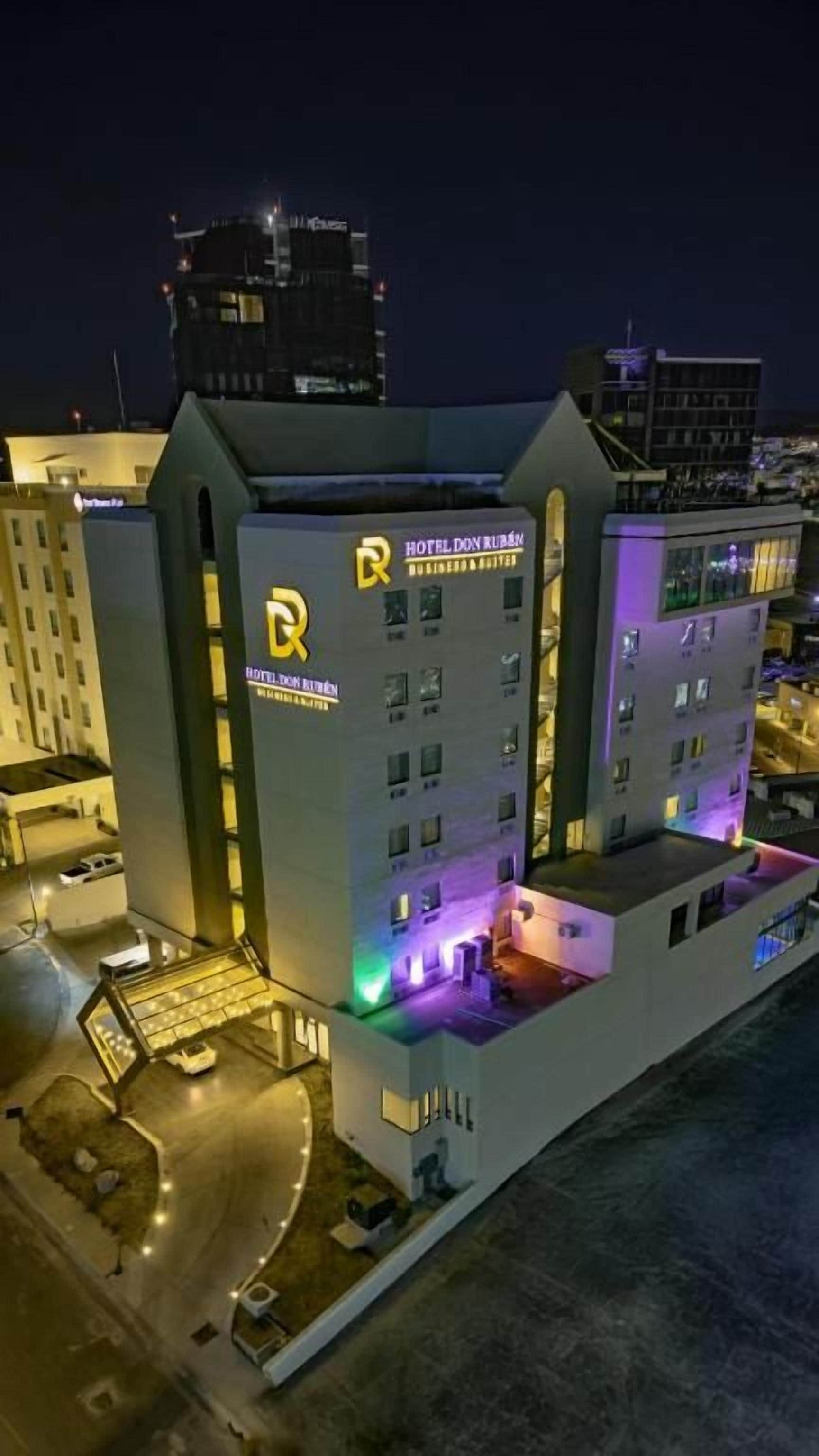 A multi-story hotel with a prominent 'HOTEL DON MEXICO' sign, a rooftop terrace, and a parking area.
