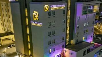 A multi-story hotel with a prominent 'HOTEL DON MEXICO' sign, a rooftop terrace, and a parking area.