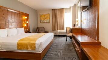 A hotel room with a large bed, a desk, a chair, a television, and a painting on the wall.
