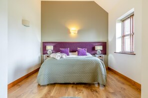 A bedroom with a large bed, two bedside tables, a headboard, a wall-mounted light, and a window with blinds. - 3 Bed in Yoxall (oc-s46074) (Hadley End)