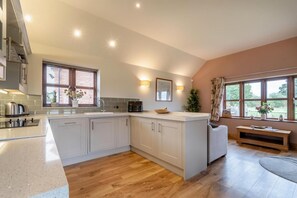 A modern kitchen with a central island, built-in appliances, and a view of the outdoors. - 2 Bed in Yoxall (oc-s46075) (Hadley End)