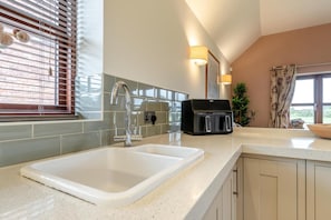 A modern kitchen with a white sink, stainless steel faucet, and a black electric kettle on the counter. - 2 Bed in Yoxall (oc-s46075) (Hadley End)