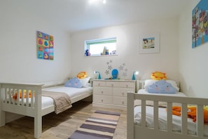 A child's bedroom with two single beds, a dresser, a window, and wall decorations. - 3 Bed in Porth (oc-b584338) (Newquay)