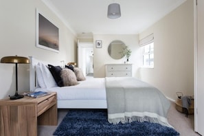 A bedroom with a bed, bedside table, lamp, dresser, and a window. - 2 Bed in Mousehole (oc-b584390) (Mousehole)
