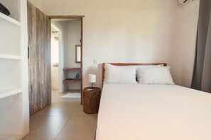 Une chambre à coucher avec un lit, une table de chevet, un miroir et une porte en bois.