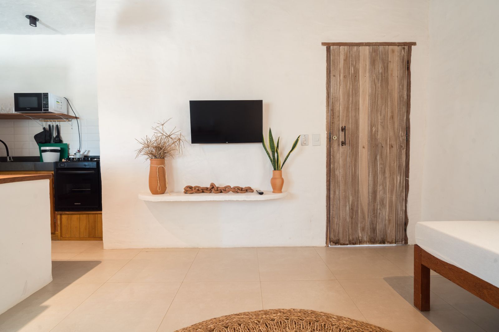 A modern kitchen with a flat-screen TV, wooden cabinets, and a rustic door.