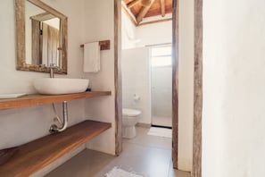 Une salle de bain avec un meuble-lavabo en bois, un lavabo blanc et un espace douche.
