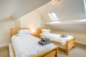 Ein Schlafzimmer mit zwei Holzbetten, einem Oberlicht und einem Nachttisch mit Lampe.