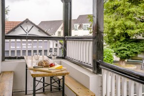 Ein Balkon mit Holztisch, Bank und Geländer.