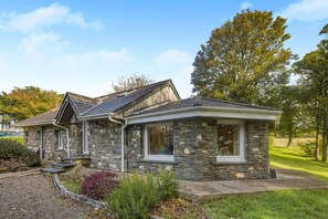 A stone house with a sloped roof and a front porch. - 2 Bed in Talgarreg (oc-b46320) (Talgarreg)