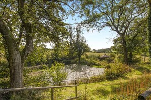 A natural landscape with a river, trees, and a gazebo. - 2 Bed in Talgarreg (oc-b46320) (Talgarreg)