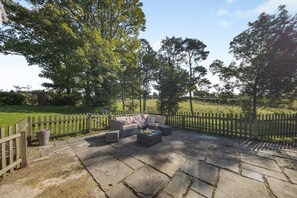 A patio with stone flooring, a wooden fence, and a seating area with a sofa and coffee table. - 2 Bed in Talgarreg (oc-b46320) (Talgarreg)
