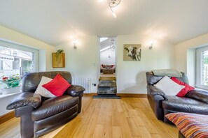 A spacious room with two leather armchairs, a wooden floor, a staircase, and a view of the outside. - 2 Bed in Talgarreg (oc-b46320) (Talgarreg)