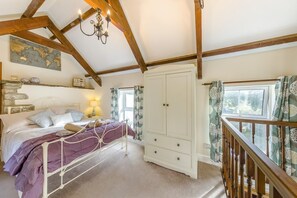 A bedroom with a bed, a wardrobe, a chandelier, a map on the wall, and a window with curtains. - 1 Bed in Talgarreg (oc-t46321) (Talgarreg)