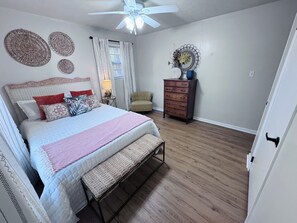 A bedroom with a bed, bedside table, lamp, chair, dresser, and decorative wall art. - The Parkway House: A peaceful 3-bedroom house on top of Lookout Mountain (Fort Payne)
