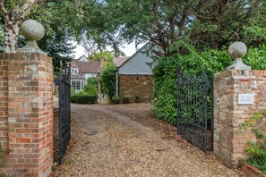 A gravel driveway leading to a gated entrance with brick walls and decorative stone balls on top. - 2 Bed in Stoke Hammond (oc-o46350) (Stoke Hammond)