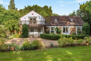 A two-story house with a balcony, a garden with various plants, and a well-maintained lawn. - 2 Bed in Stoke Hammond (oc-o46350) (Stoke Hammond)