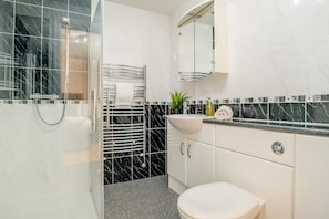 A bathroom with a glass shower enclosure, a white sink with a marble countertop, and a toilet. - 4 Bed in Chathill (oc-e42807) (Ellingham)