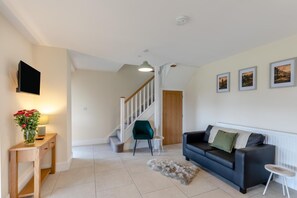 A living room with a sofa, a small table, a chair, a rug, and a staircase. - 5 Bed in Newbridge-on-Wye (oc-u46325) (Newbridge on Wye)