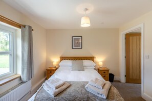 A neatly made bed with pillows and two bedside tables with lamps, a framed picture on the wall, and a window with curtains. - 5 Bed in Newbridge-on-Wye (oc-u46325) (Newbridge on Wye)