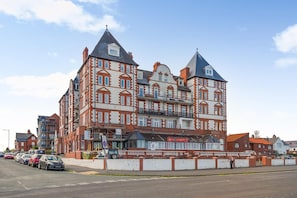 A multi-story building with a prominent corner entrance, a balcony, and a visible sign for a business. - 2 Bed in Whitby (oc-s46340) (Whitby)