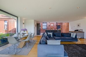 Uma sala de estar moderna com sofá, mesa de jantar e área de cozinha, com paredes de tijolo.