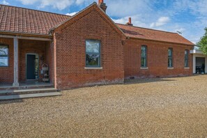 A red brick building with a tiled roof, a gravel driveway, and a door with a window. - 3 Bed in Roughton (oc-e46003) (Roughton)