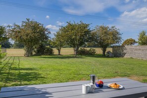 A picnic table with a metal container, two mugs, and a plate with food. - 3 Bed in Roughton (oc-e46003) (Roughton)