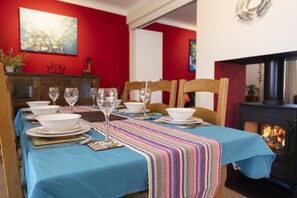 Ein Esszimmer mit blauem Tischtuch, weißem Geschirr und einer Streifenläuferbahn.