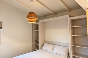 Un dormitorio con cama, estanterías empotradas y una lámpara colgante.