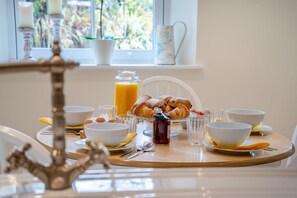A breakfast table with croissants, bowls, a pitcher of orange juice, and a candle holder. - 3 Bed in Penpedairheol (oc-o46341) (Penpedairheol)