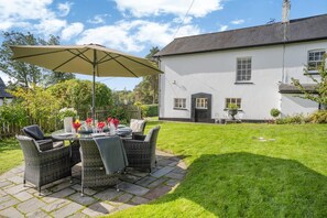 A patio with a round table, chairs, and an umbrella. - 3 Bed in Penpedairheol (oc-o46341) (Penpedairheol)